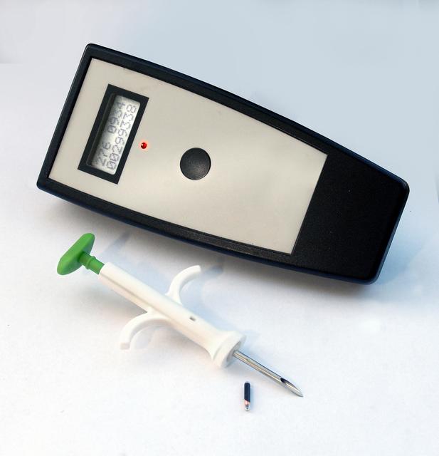 Einwegspritze, Mikrochip und ein kleiner Handscanner, mit dem die Daten des Chips berührungslos ausgelesen werden