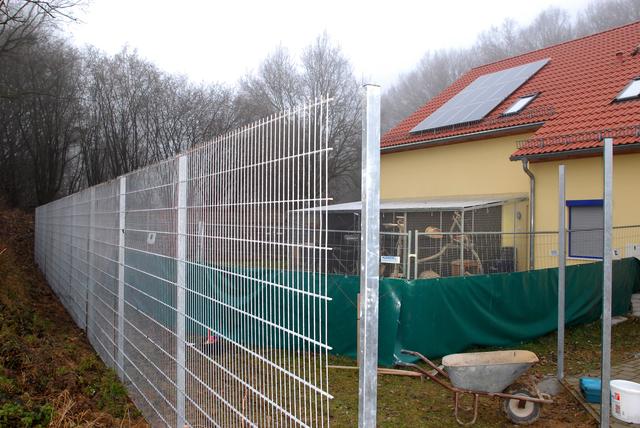 Der neue Bauzaun rund um die Tierherberge wird derzeit aufgebaut. Im Hintergrund der bisherige, deutlich niedrigere Bauzaun