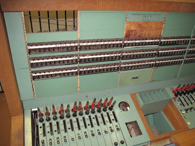 Detail eines Arbeitsplatzes der Fernsprechvermittlung, deren Technik größtenteils ausgebaut wurde. Bei einem eingehenden Anruf wurde mit dem roten Stecker die Verbindung angenommen und nach Abfragen des gewünschten Kontakts mit dem schwarzen Stecker die Verbindung hergestellt. Alles wurde per Hand „gestöpselt“ (2014).