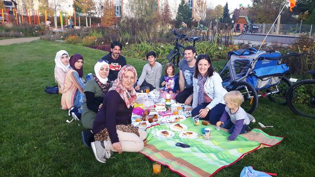 Zwei Familien, die am Kita-Patenschaftsprojekt teilnehmen, beim Picknick im Bürgerpark