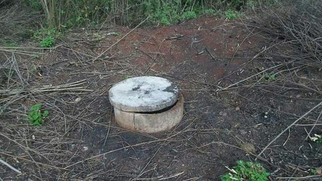 Gebohrter Brunnen ohne Einfassung und Wasserpumpe