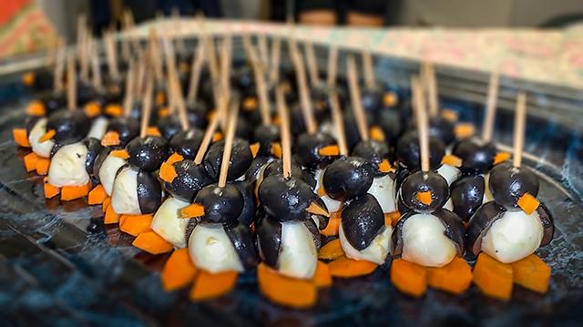 Tiere am vegetarischen Buffet? "Pinguine", aufgespießt durch den Kopf? In einem Tierheim?! Man nehme pro Tier: 1 Kügelchen Mozzarella, für Kopf und schwarzer Frack 1 ½ Oliven, Schnabel, die Watschelfüßchen und Schnabel bestehen aus aus Karotten. Selbstgemacht von einer Mitarbeiterin, versteht sich.