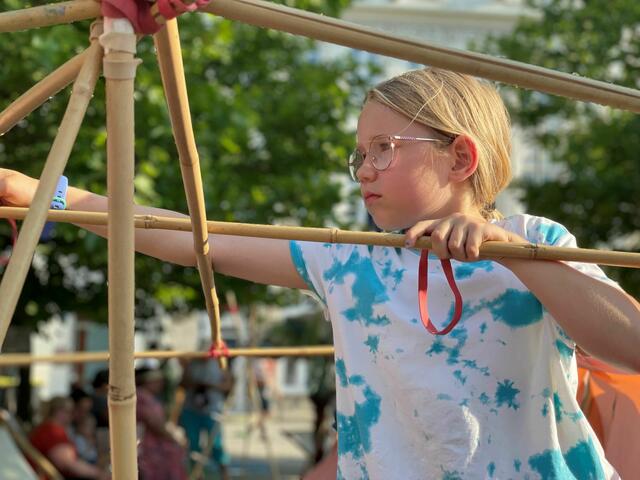 Ganz konzentriert verbindet dieses Mädchen die Bambusstäbe. 