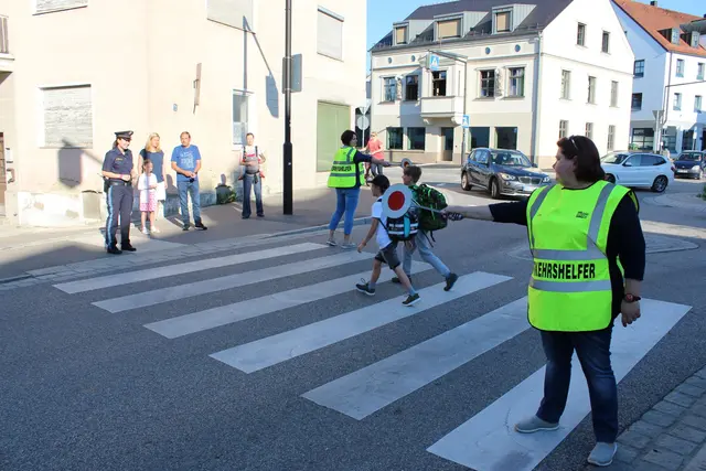 Schulweghelfer helfen Kindern wie hier an der Scheyerer Straße beim Überqueren der Straße.