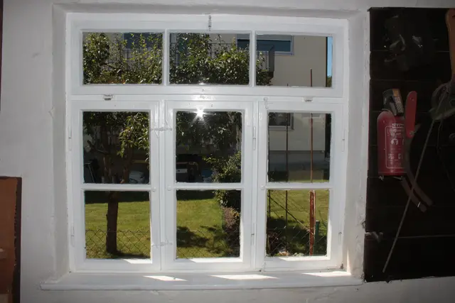 Ein Schreinereifenster aus der Bauzeit mit schönen Griffen