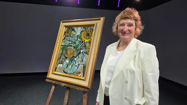 Karin Probst steht neben einem Gemälde auf einer Staffelei