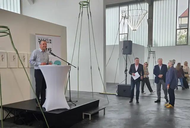Bürgermeister an Stehtisch mit Mikrofon in der Kunsthalle, Menschen außen herum