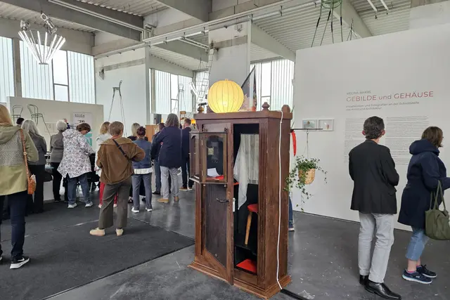 Menschen in der Kunsthalle betrachten Werke, ein Schrank als Kunstwerk in der Mitte
