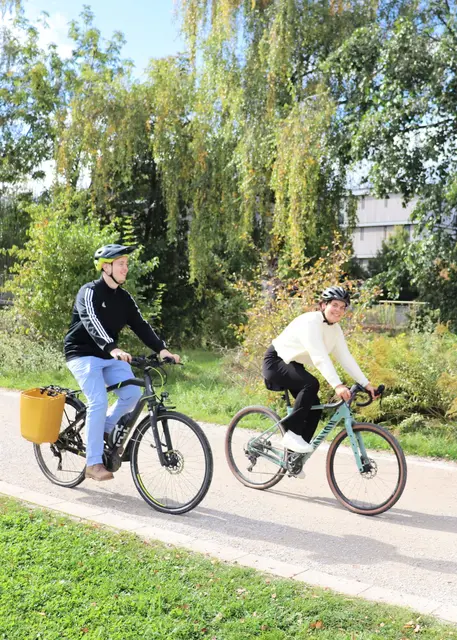 ein Mann und eine Frau radeln durch einen Park