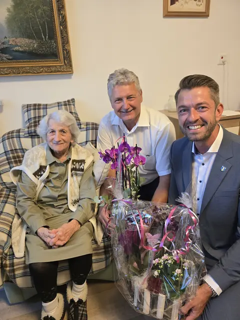 v. l.: Hilda Sellner sitzt in einem Sessel, Zweiter Bürgermeister Peter Heinzlmair und Stellvertreter des Landrats Georg Ott