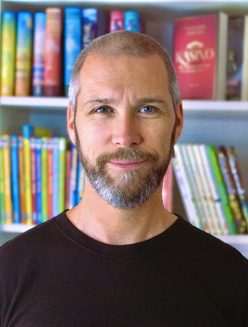 Portrait-Aufname von Heiko Wolz, im Hintergrund ein Bücherregal