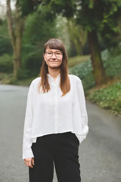 Elena Fischer steht auf einem Weg, im Hintergrund Bäume und Gras