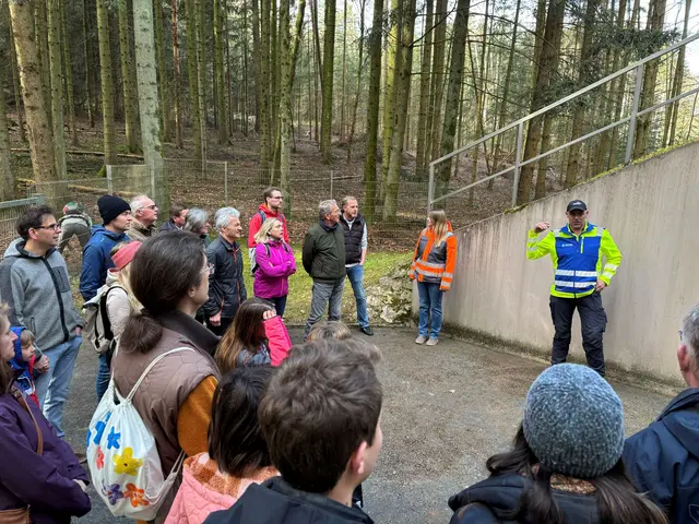 Draußen steht eine Gruppe Menschen und hört einem Sprecher zu.