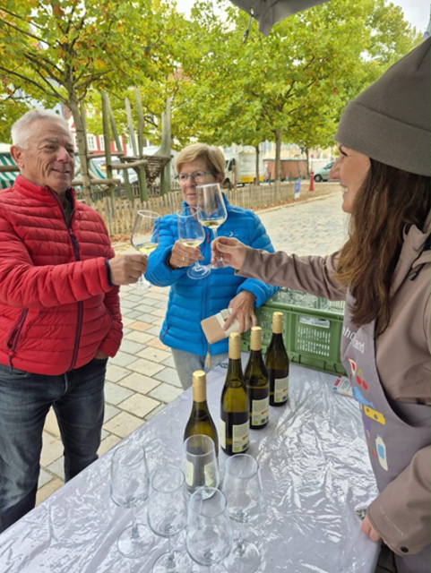 Ein älteres Paar stößt mit der Mitarbeiterin mit Weingläsern an