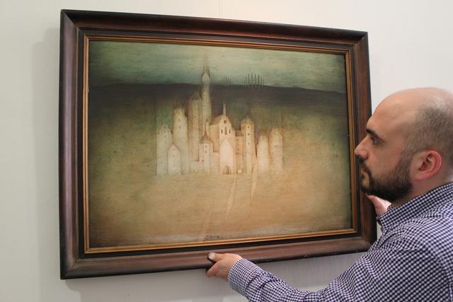Der städtische Kulturmanager Sebastian Daschner hängt ein Bild von Dieter Eckert  mit dem Titel „Pfaffenhofen“ aus dem Jahr 1982.